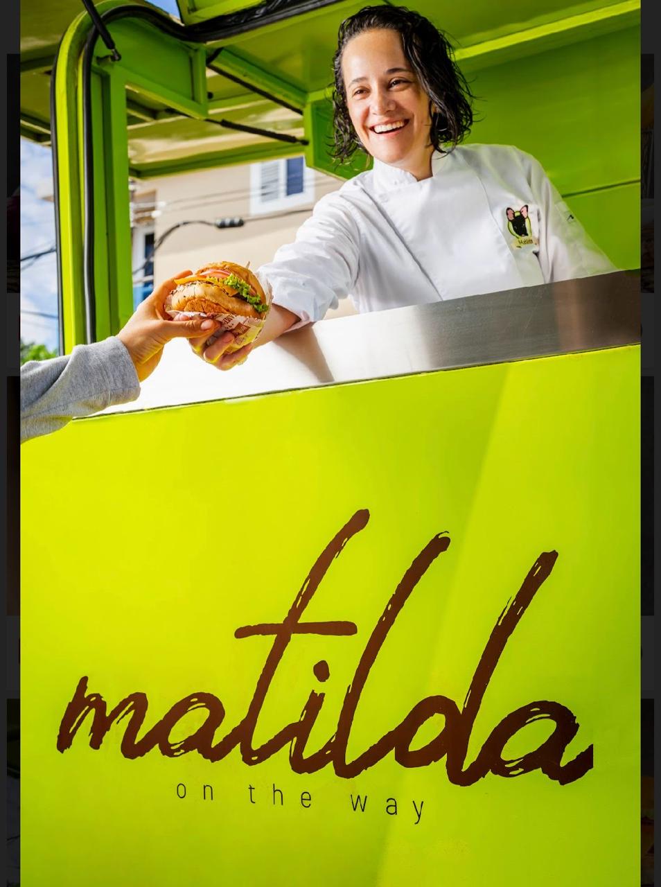 Cocinera de Matilda entregando una hamburguesa por la ventanilla